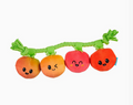 A plush dog toy shaped like a branch with four cartoon fruit characters attached, including orange, yellow, pink, and red fruits with black eyes and smiling faces, on a plain white background.