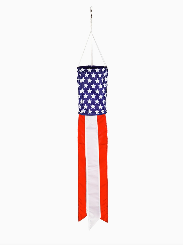An American flag wind spinner hanging from a metal hook with white strings, featuring a blue section with white stars and red and white vertical stripes.